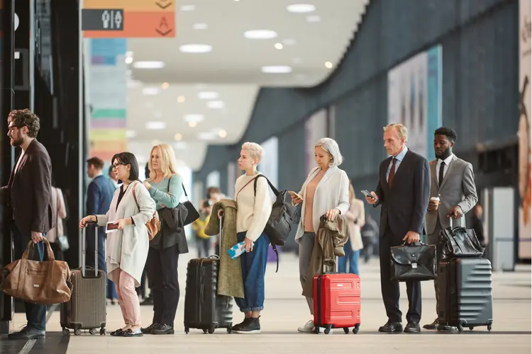 Business and leisure travelers waiting in a busy airport terminal, representing travel intent and geo-fenced audience targeting.