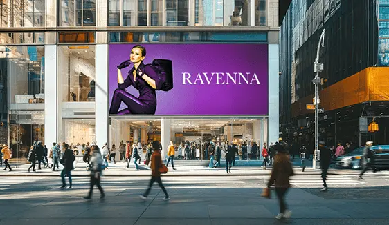 Large digital billboard on a city building displaying a fashion advertisement as pedestrians walk through a busy urban storefront area.