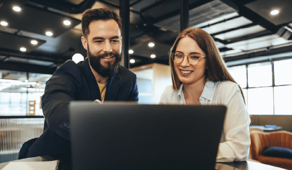 Two marketers reviewing plans on a laptop, illustrating scalable multi-location digital marketing efforts.