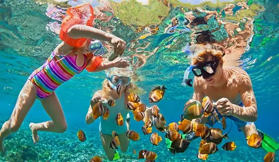 Family snorkeling in clear water during a vacation, showing how addressable geo-fencing reaches travelers at the household level.