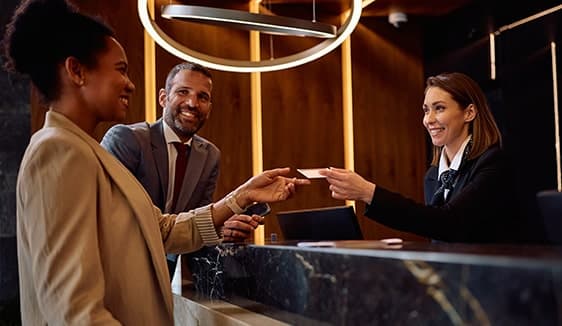 Hotel guests checking in at the front desk, reflecting how travel campaigns drive bookings and measurable foot-traffic attribution.