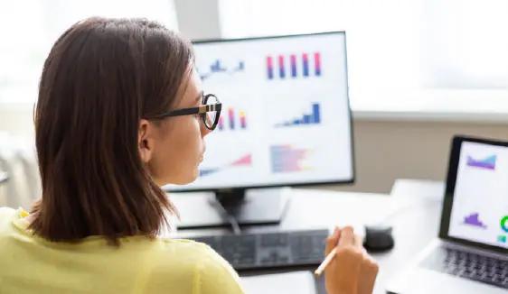 Marketer reviewing video performance metrics on multiple screens, highlighting transparent reporting and real-time insights.