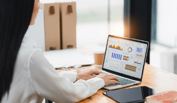 A person looking at a laptop screen with charts and graphs